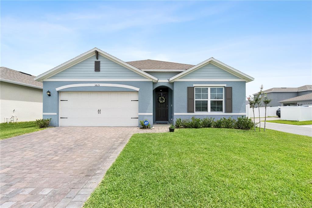 A single-story blue house with a two-car garage and a paved driveway — 5825 ARBORETUM STREET, ST CLOUD, FL