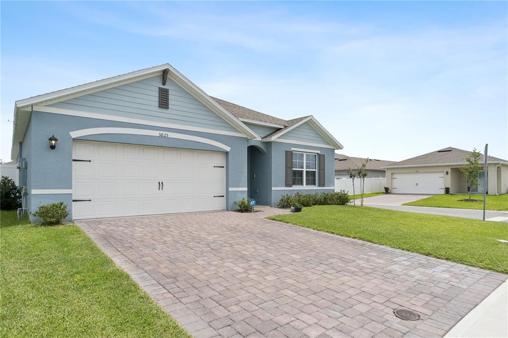 A light blue single-story house features a paved driveway and a two-car garage — 5825 ARBORETUM STREET, ST CLOUD, FL