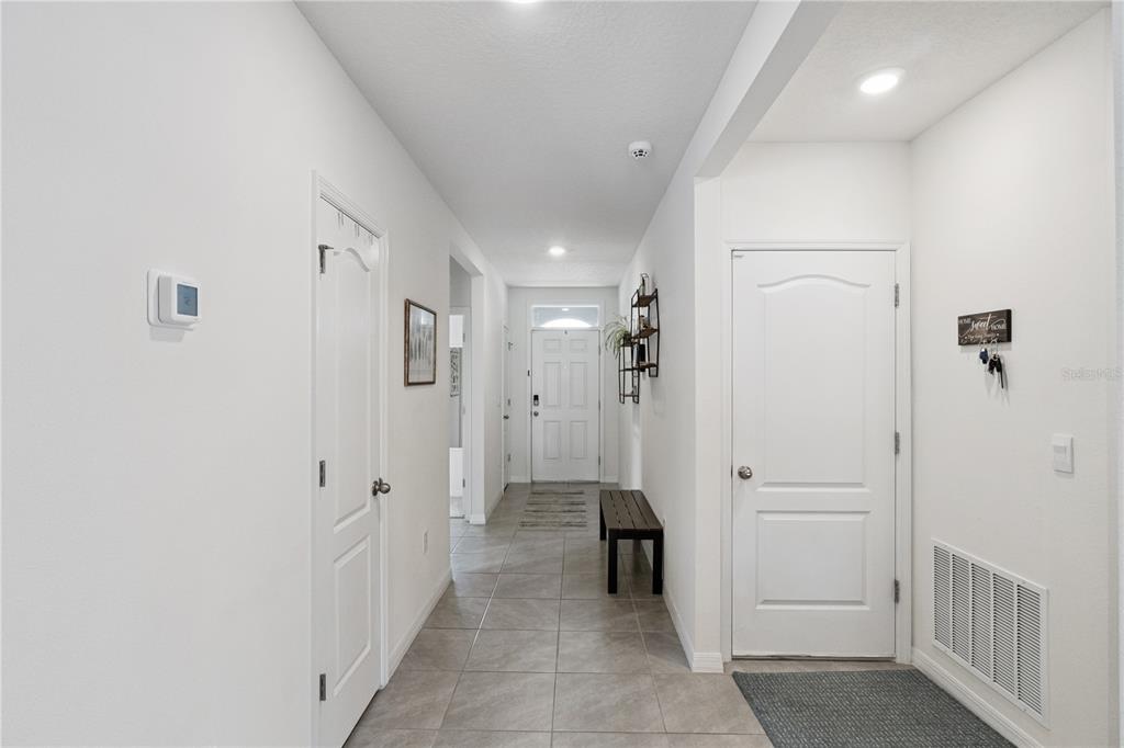 A bright entryway features tiled floors, white walls, and doors leading to other rooms — 5825 ARBORETUM STREET, ST CLOUD, FL