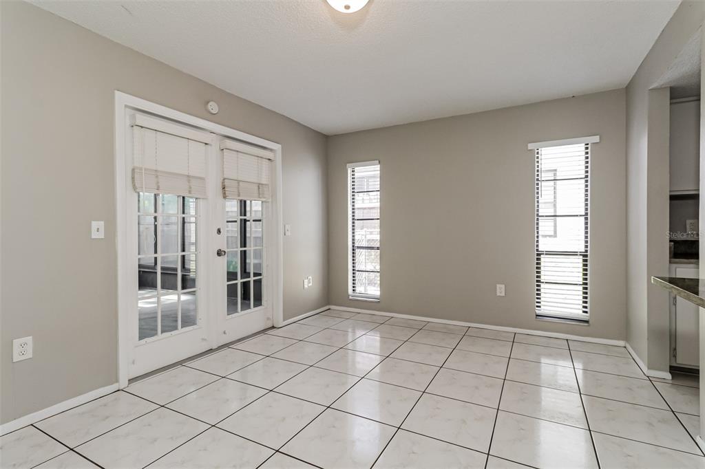 A dining area with white tile flooring, beige walls, two windows, and glass French doors — 11322 WOLF COURT, PORT RICHEY, FL