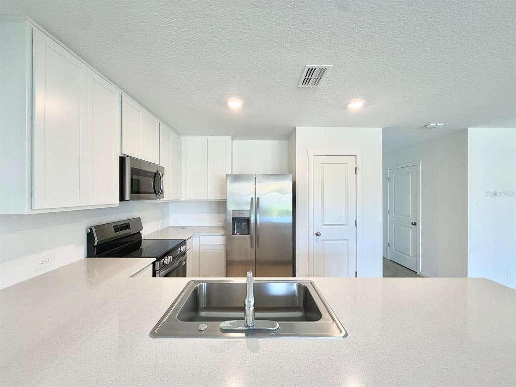 A kitchen features white cabinets, stainless steel appliances, and a central island with a sink — 836 LYNX STREET, DAVENPORT, FL