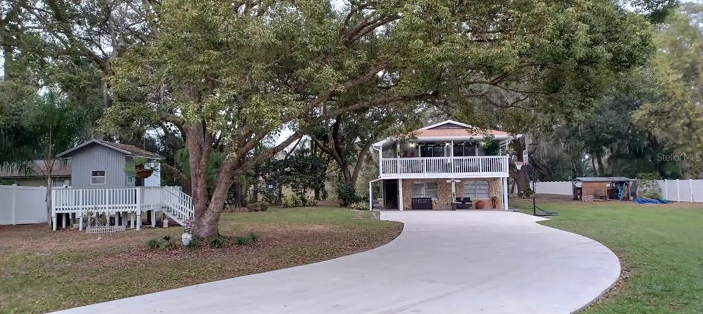 A two-story house with a white deck and a detached shed sits on a lawn — 17430 BLACKWELL LANE, LUTZ, FL