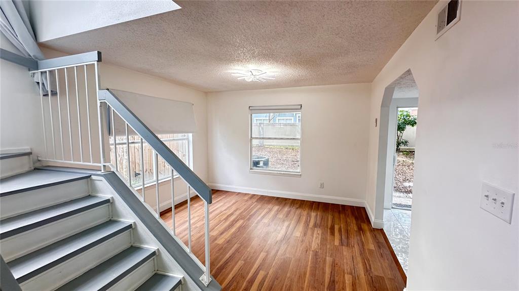 An empty room features wood-look flooring, white walls, two windows, and a ceiling light fixture — 2320 PEBBLE BROOK ROAD, KISSIMMEE, FL