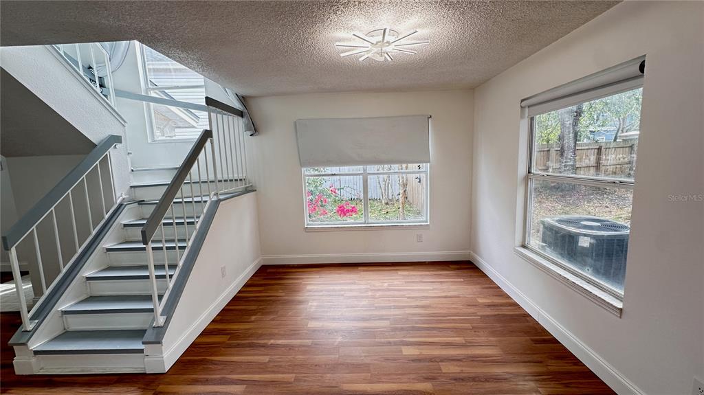 An interior view shows a room with wood-look flooring, a staircase, and a window — 2320 PEBBLE BROOK ROAD, KISSIMMEE, FL