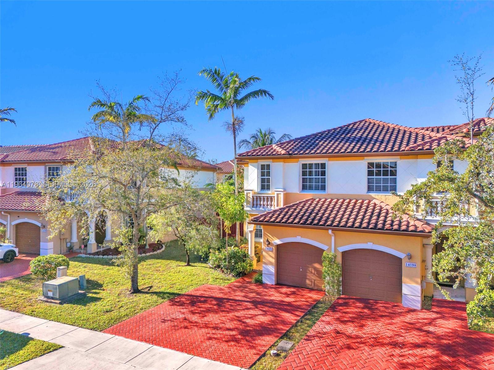 Two-story townhouses with red tile roofs and brick driveways under a clear blue sky — 14092 SW 51st Ct, Miramar FL 33027, MIRAMAR, FL