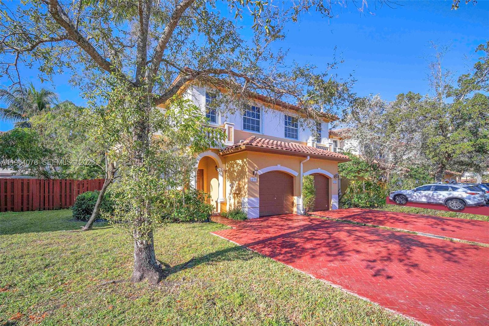A two-story yellow stucco house features a red brick driveway and two garage doors — 14092 SW 51st Ct, Miramar FL 33027, MIRAMAR, FL