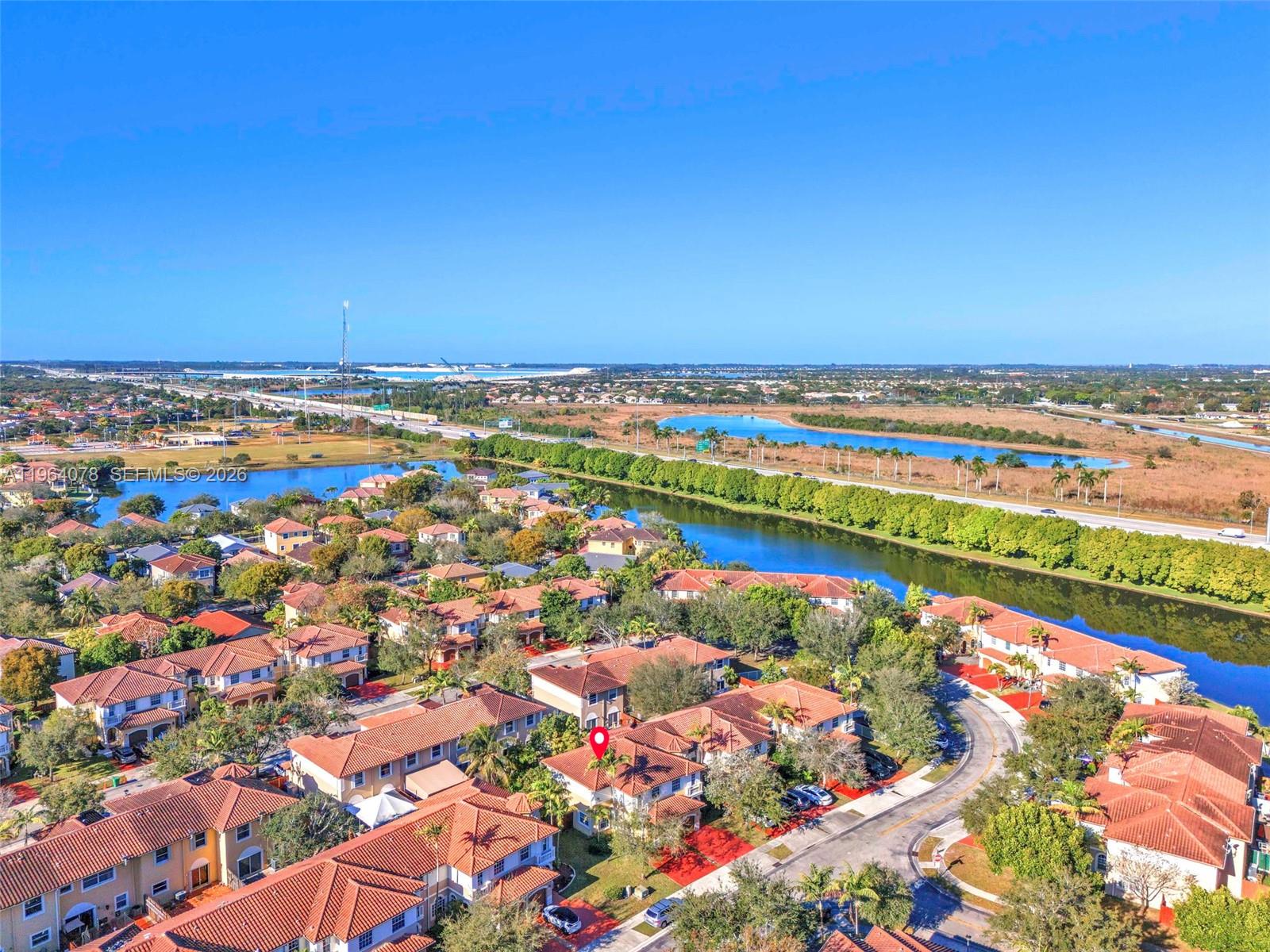 An aerial view shows a residential neighborhood with red-tiled roofs near a canal and highway — 14092 SW 51st Ct, Miramar FL 33027, MIRAMAR, FL