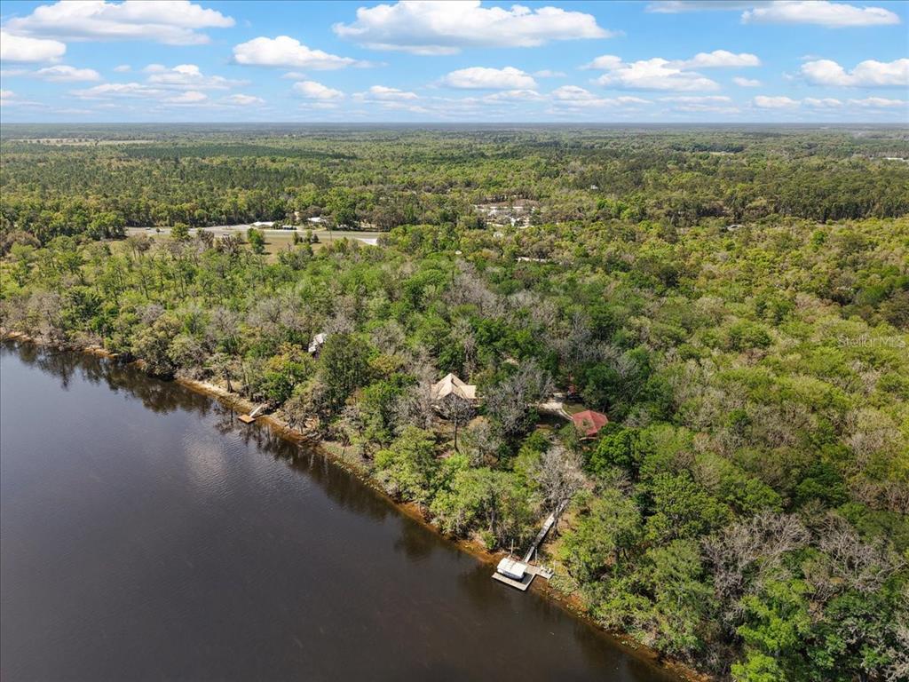 An aerial view shows a house and a dock situated along a wooded riverbank — 124 NE 824TH STREET, OLD TOWN, FL