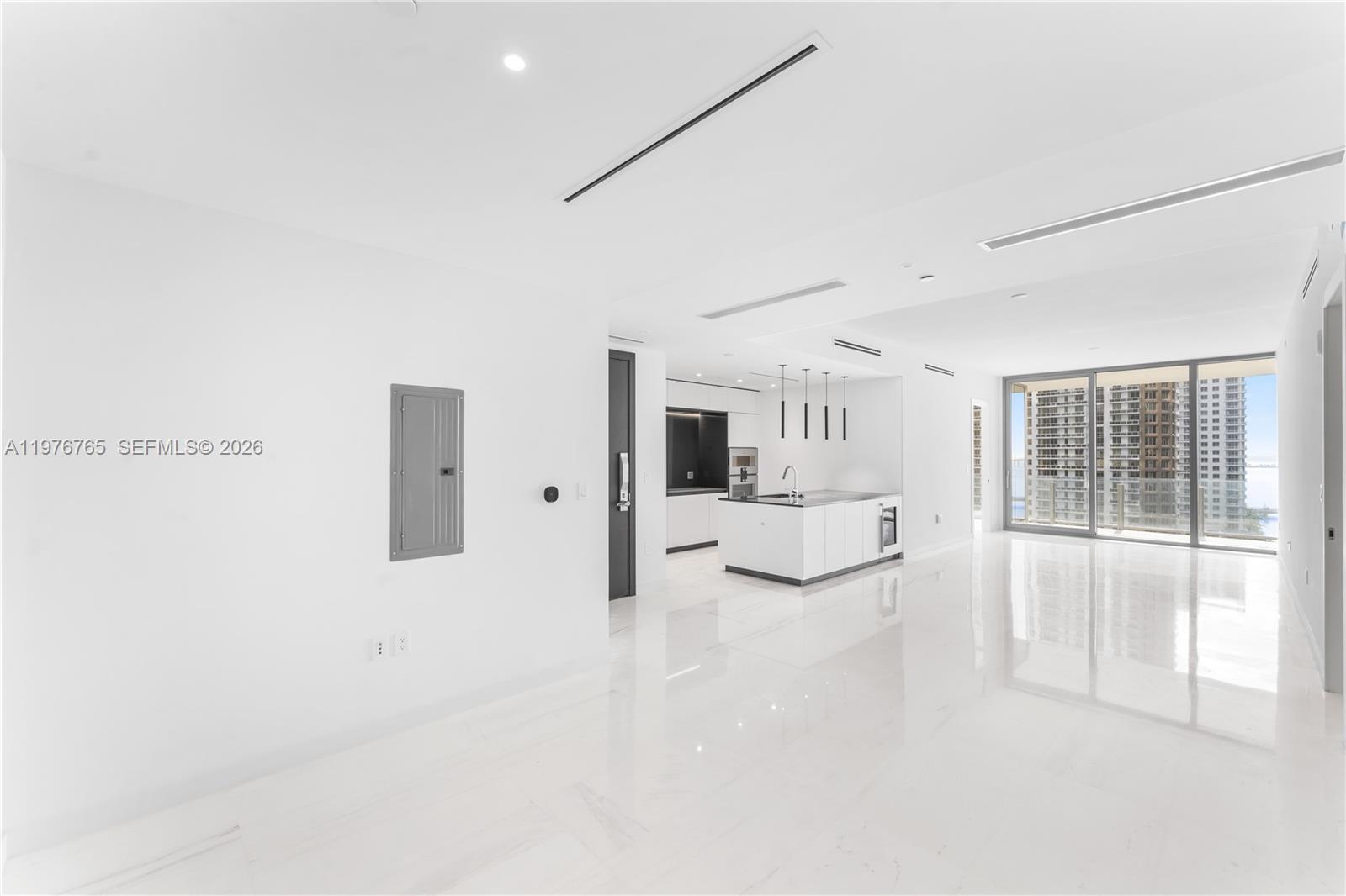 A modern, minimalist kitchen and living area features white marble floors and floor-to-ceiling windows — 300 Biscyane Blvd Way # 1202, Miami FL 33131, MIAMI, FL