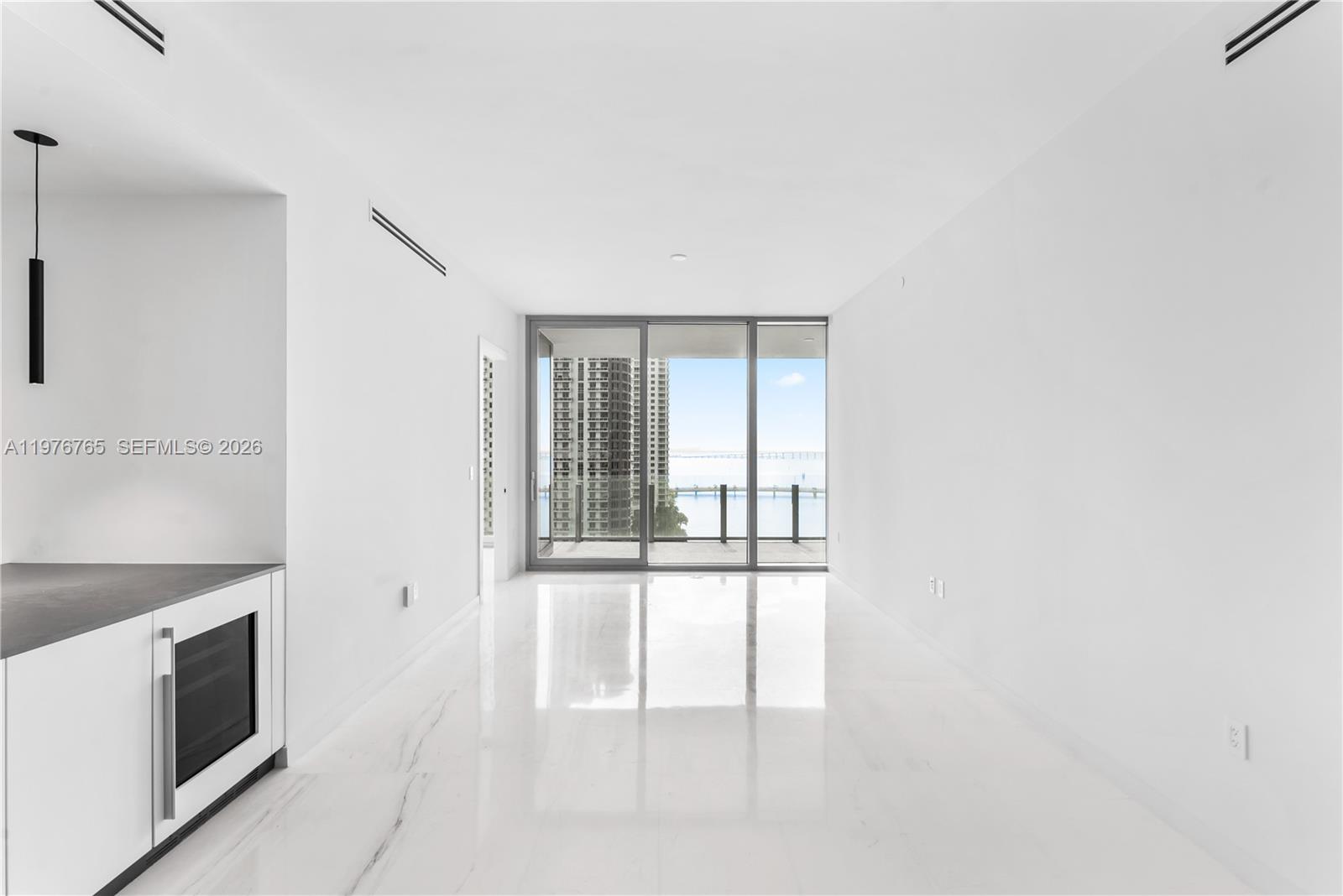 A minimalist living area features white marble floors, a wine cooler, and floor-to-ceiling balcony windows — 300 Biscyane Blvd Way # 1202, Miami FL 33131, MIAMI, FL