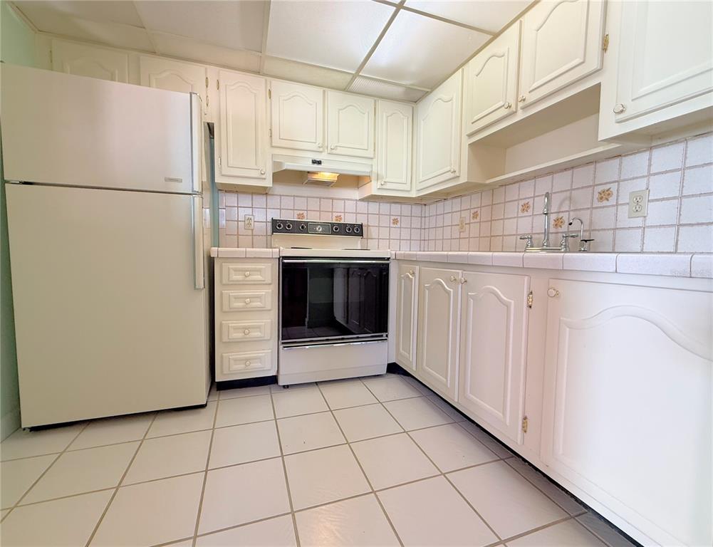 A kitchen features white cabinets, white tile countertops, a white refrigerator, and a white stove — 11931 BAYONET LANE, NEW PORT RICHEY, FL