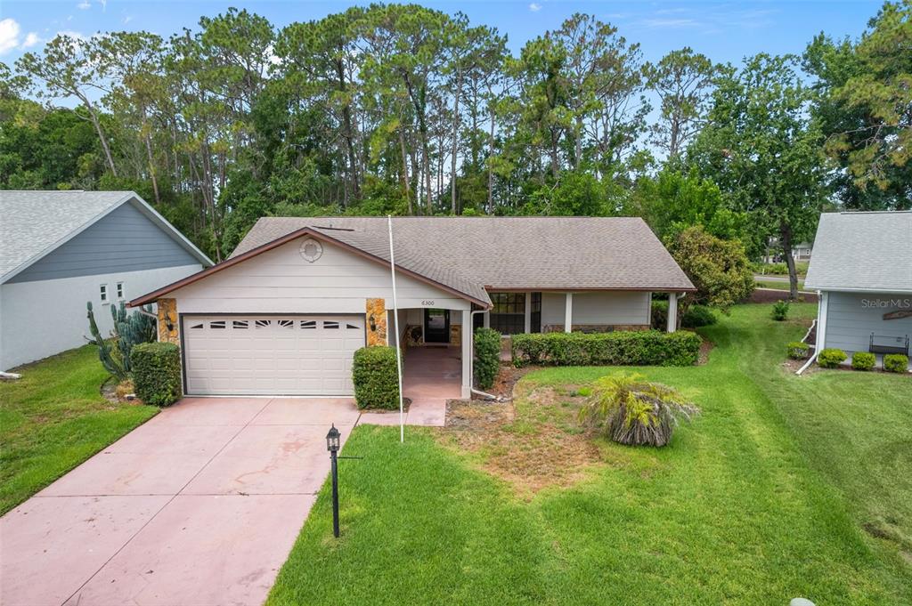 An exterior view of a single-story house with a garage, driveway, and surrounding lawn — 6300 DARIEN WAY, SPRING HILL, FL