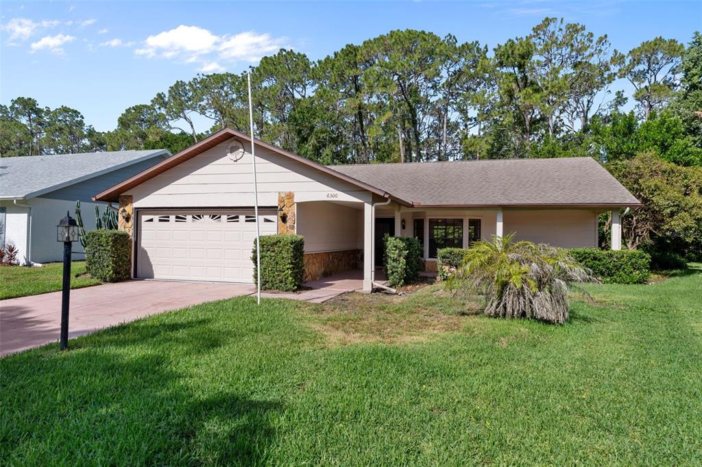 A single-story house with a beige exterior, stone accents, and a two-car garage — 6300 DARIEN WAY, SPRING HILL, FL
