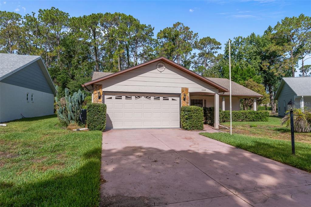 A single-story house with a beige exterior, a two-car garage, and a concrete driveway — 6300 DARIEN WAY, SPRING HILL, FL