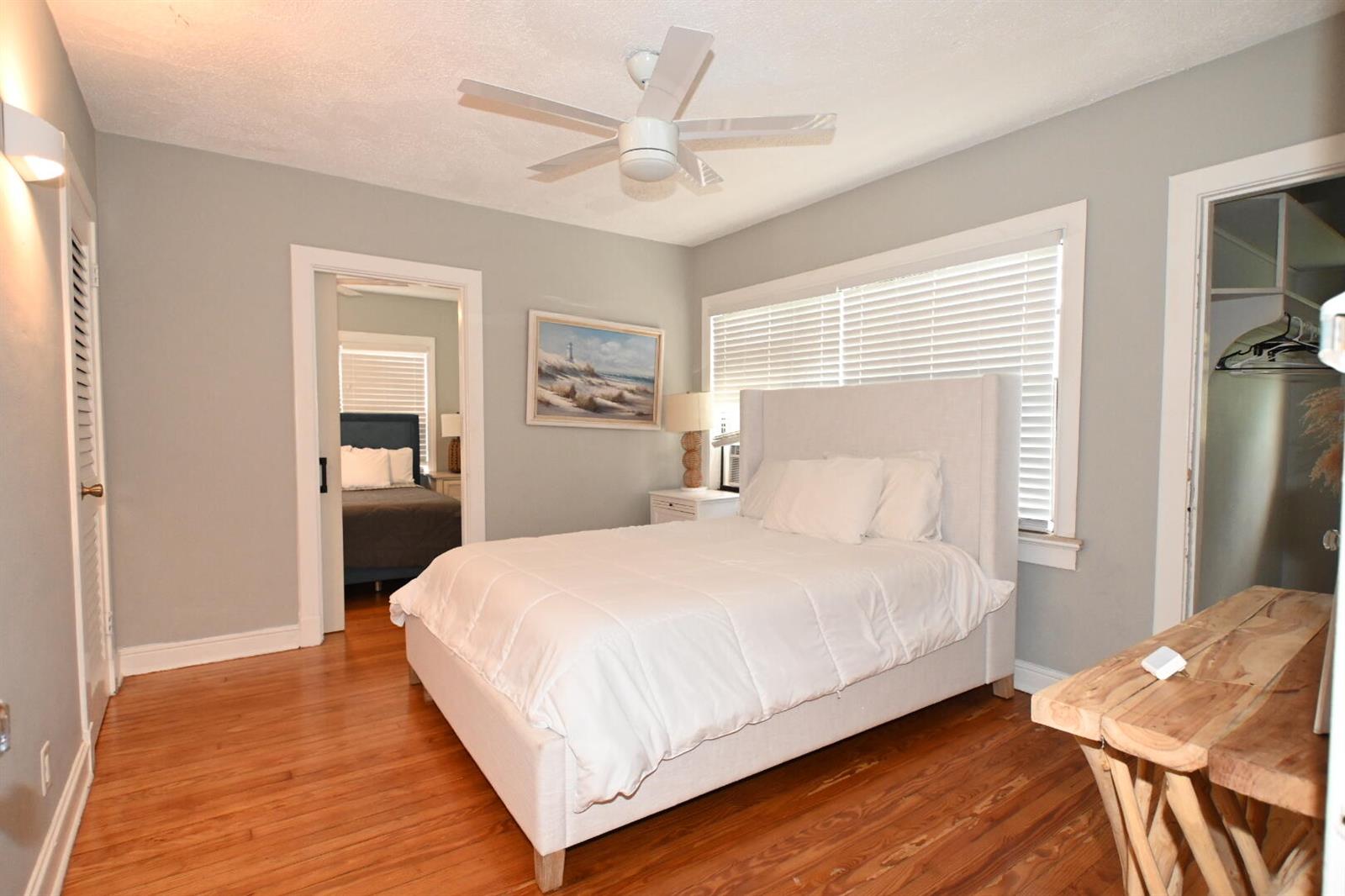 A bedroom features a white upholstered bed, hardwood floors, a ceiling fan, and a closet — 701 W Ocean Avenue, Boynton Beach FL 33426, BOYNTON BEACH, FL