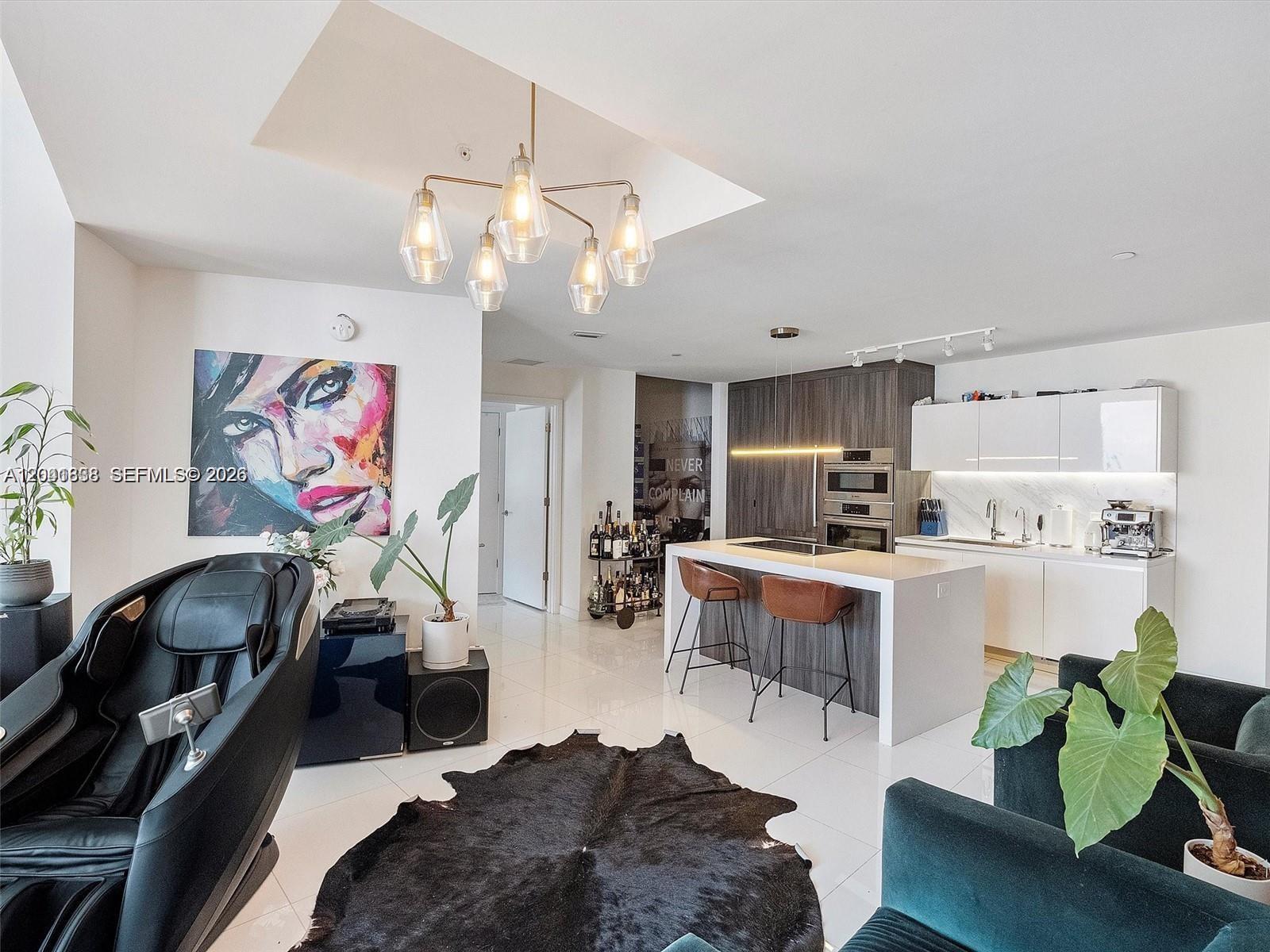 A modern open-concept living area features a kitchen with an island and a massage chair — 851 NE 1st Ave # 4109, Miami FL 33132, MIAMI, FL