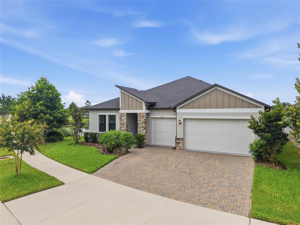 A single-story house with a stone-accented entrance, a two-car garage, and a paved driveway — 21676 SNOWY ORCHID TERRACE, LAND O LAKES, FL