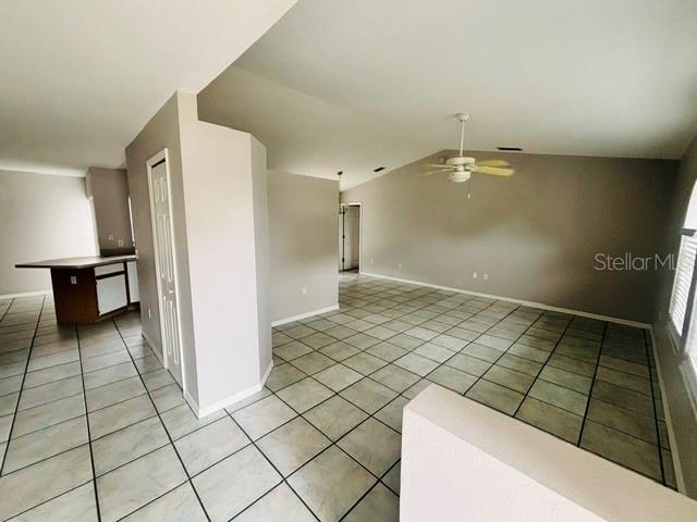 An open-concept living area features light-colored tile flooring, a vaulted ceiling, and a ceiling fan — 2830 ASCOT LANE, DELTONA, FL