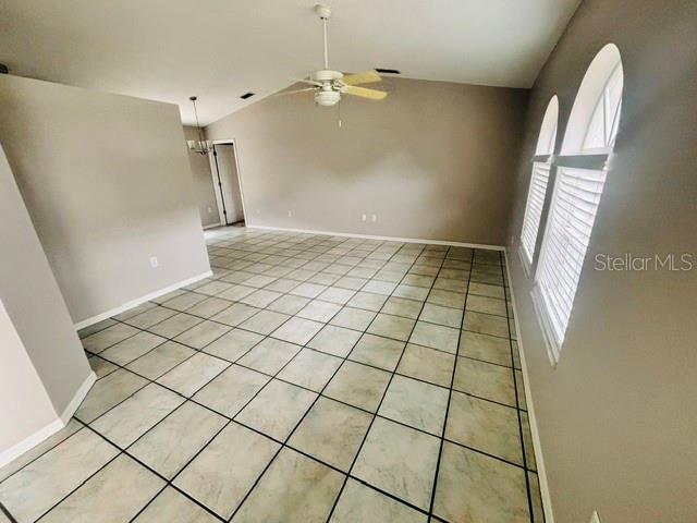 An empty room features light-colored tile flooring, a ceiling fan, and two arched windows — 2830 ASCOT LANE, DELTONA, FL