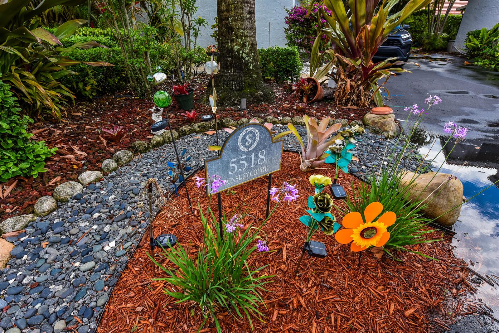 A house address sign stands in a landscaped garden bed with mulch and decorative ornaments — 5518 Ainsley Court, Boynton Beach FL 33437, BOYNTON BEACH, FL