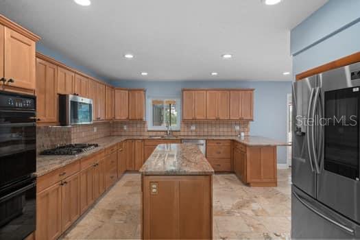 A kitchen features wood cabinets, granite countertops, a central island, and stainless steel appliances — 2309 CYPRESS WALK WAY, RUSKIN, FL