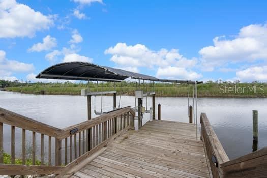 A wooden dock with a boat lift extends over a calm body of water — 2309 CYPRESS WALK WAY, RUSKIN, FL