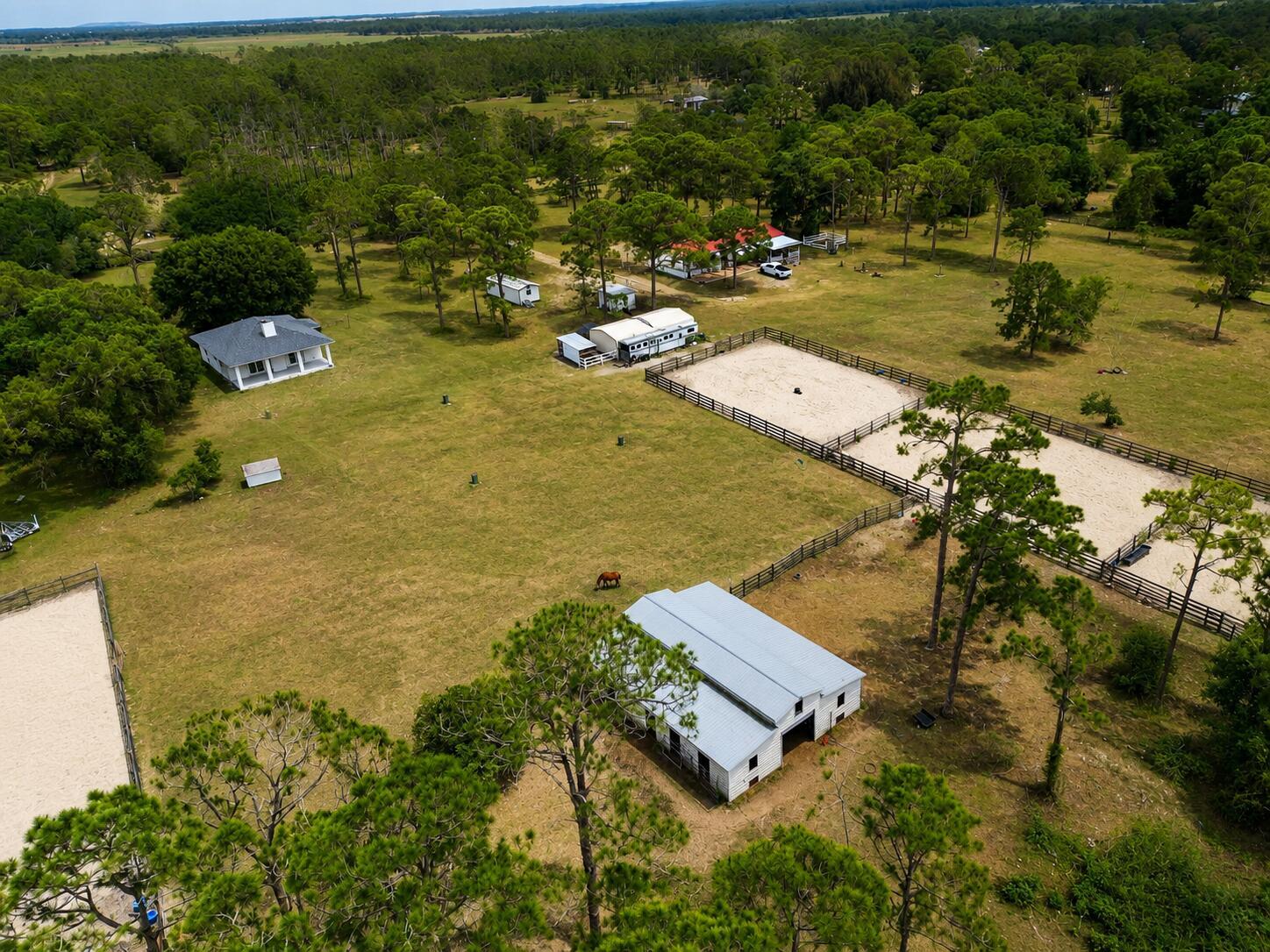 An aerial view shows two houses, a fenced paddock, and outbuildings on a wooded lot — 12851 NE 26th Avenue, Okeechobee FL 34972, OKEECHOBEE, FL