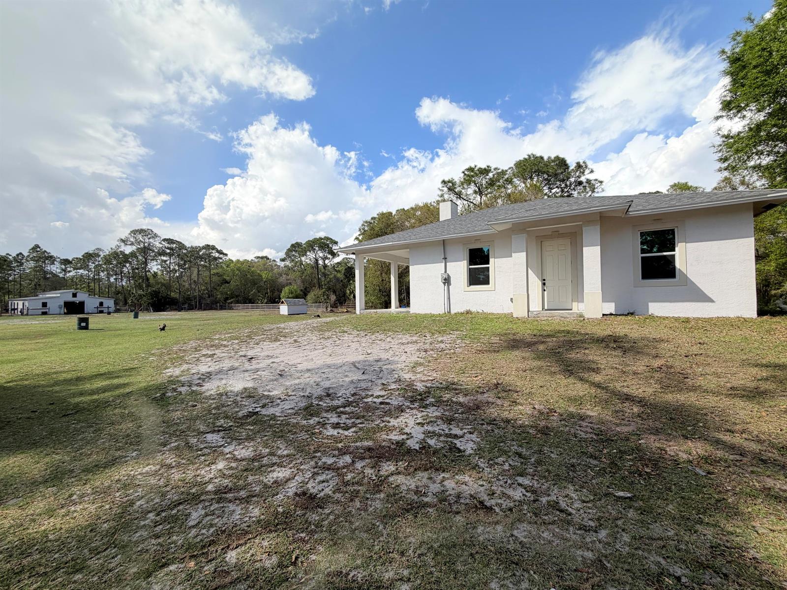 A view from a covered patio overlooking a large grassy field with several outbuildings — 12851 NE 26th Avenue, Okeechobee FL 34972, OKEECHOBEE, FL