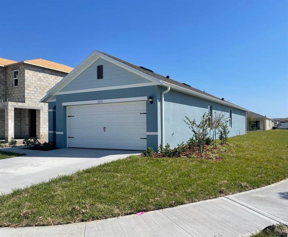 A blue single-story house with a two-car garage and a concrete driveway — 1533 QUINTA ROAD, KISSIMMEE, FL