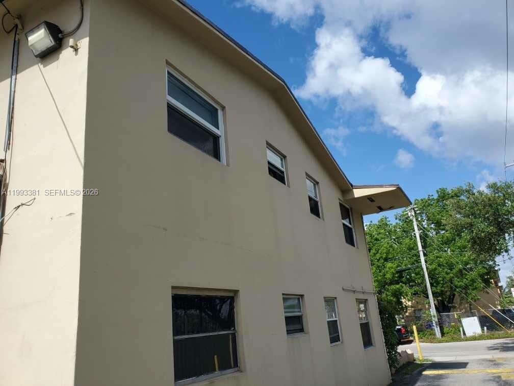A low-angle exterior view of a two-story beige building with multiple windows — 3901 SW 78th Ct # 221, Miami FL 33155, MIAMI, FL