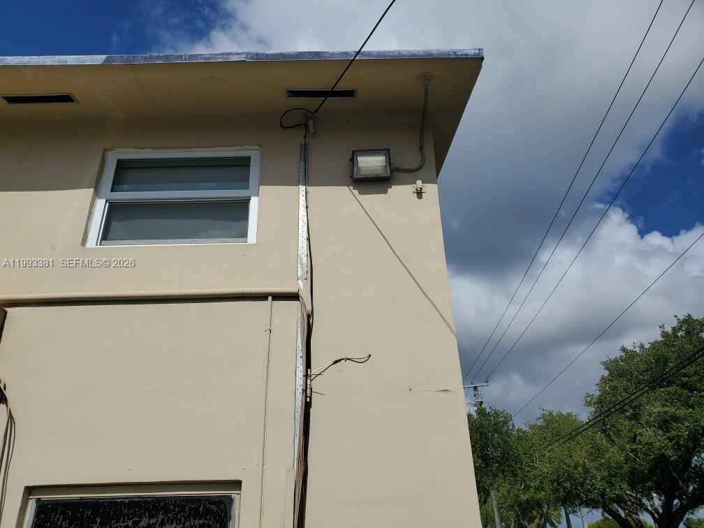 The exterior of a tan building features a window, a light fixture, and exposed wiring — 3901 SW 78th Ct # 221, Miami FL 33155, MIAMI, FL