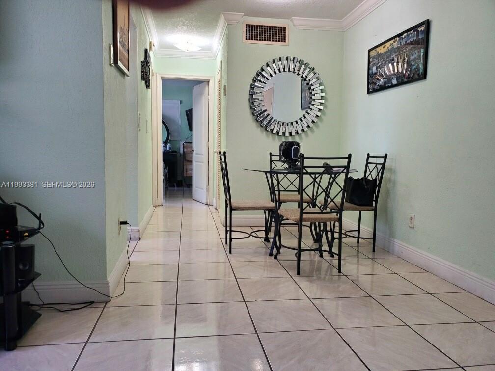 A dining area with a glass table, metal chairs, and a round mirror on the wall — 3901 SW 78th Ct # 221, Miami FL 33155, MIAMI, FL