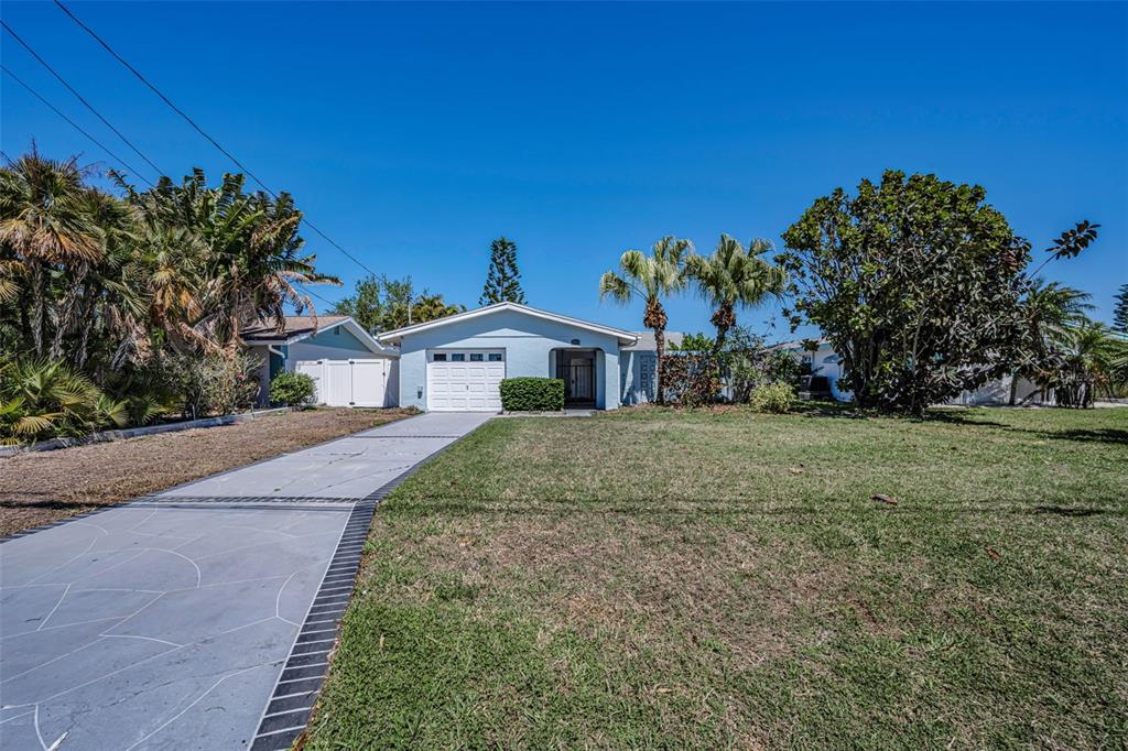 A single-story house with a light blue exterior, a paved driveway, and palm trees — 3931 HEADSAIL DRIVE, NEW PORT RICHEY, FL