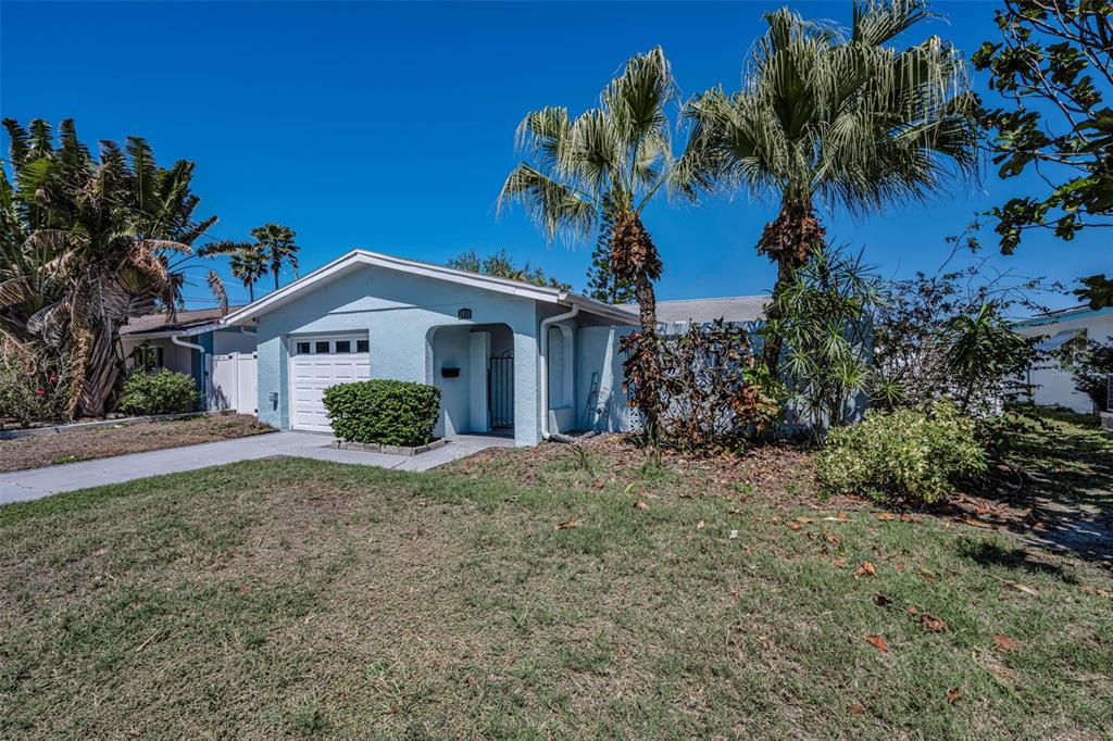 A light blue single-story house features a small garage, palm trees, and a grassy yard — 3931 HEADSAIL DRIVE, NEW PORT RICHEY, FL