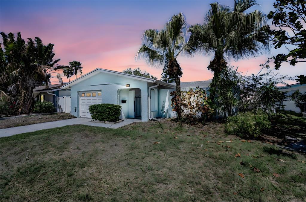 A light blue single-story house with a garage and palm trees under a sunset sky — 3931 HEADSAIL DRIVE, NEW PORT RICHEY, FL