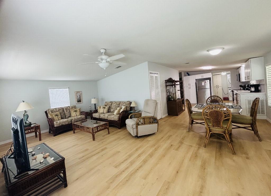 An open-concept living and dining area features light wood flooring and tropical-style furniture — 6191 TERN DRIVE, ENGLEWOOD, FL