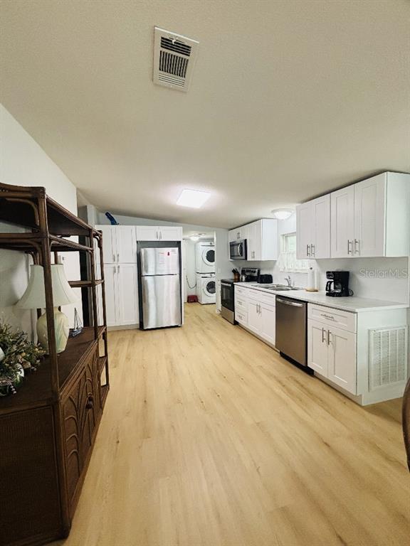 A kitchen features white cabinetry, stainless steel appliances, and light wood-look flooring — 6191 TERN DRIVE, ENGLEWOOD, FL