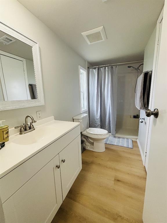 A bathroom features a white vanity, a toilet, and a shower with a gray curtain — 6191 TERN DRIVE, ENGLEWOOD, FL