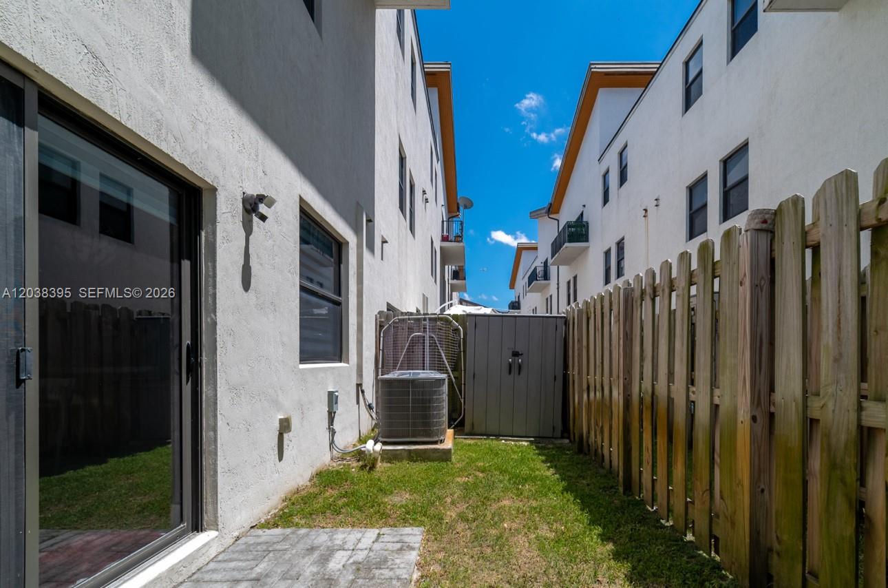 A narrow backyard features a small patch of grass, an air conditioning unit, and fencing — 10443 NW 82nd St # 8, Doral FL 33178, DORAL, FL