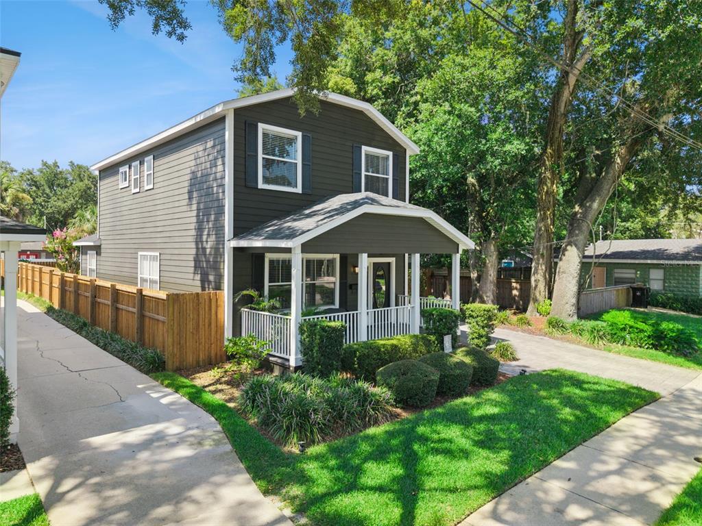 A two-story house with dark gray siding, a front porch, and a wooden fence — 1810 ILLINOIS STREET, ORLANDO, FL