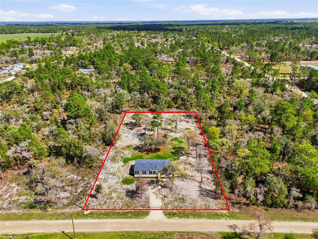 An aerial view shows a single-story house centered on a large, fenced, wooded lot — 2231 SE 132ND COURT, MORRISTON, FL