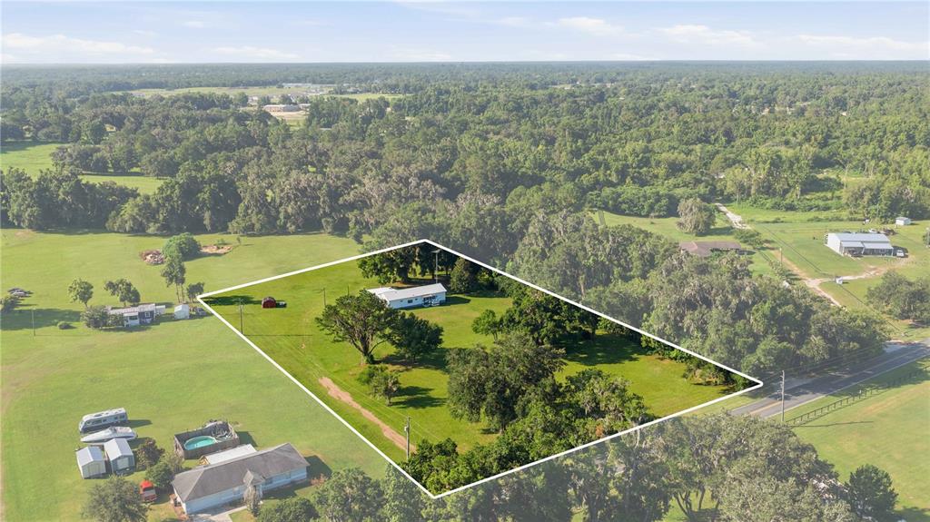 An aerial view shows a house on a large, grassy lot with scattered trees — 4950 SE 112TH STREET ROAD, BELLEVIEW, FL