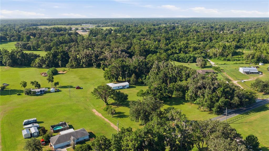 An aerial view shows a rural property with multiple houses, outbuildings, and trees on grass — 4950 SE 112TH STREET ROAD, BELLEVIEW, FL