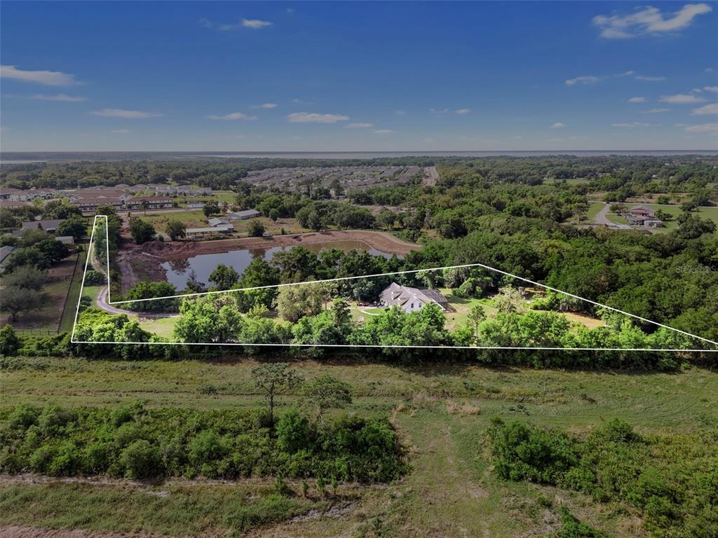 An aerial view shows a house on a large, wooded lot with a private pond — 4385 BOGGY CREEK ROAD, KISSIMMEE, FL