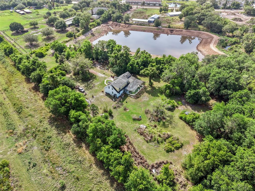 An aerial view shows a house with a screened porch situated near a large pond — 4385 BOGGY CREEK ROAD, KISSIMMEE, FL