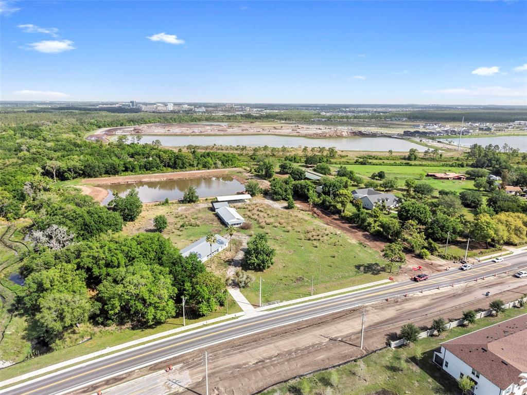 An aerial view shows a rural property with two buildings, a pond, and a road — 4385 BOGGY CREEK ROAD, KISSIMMEE, FL