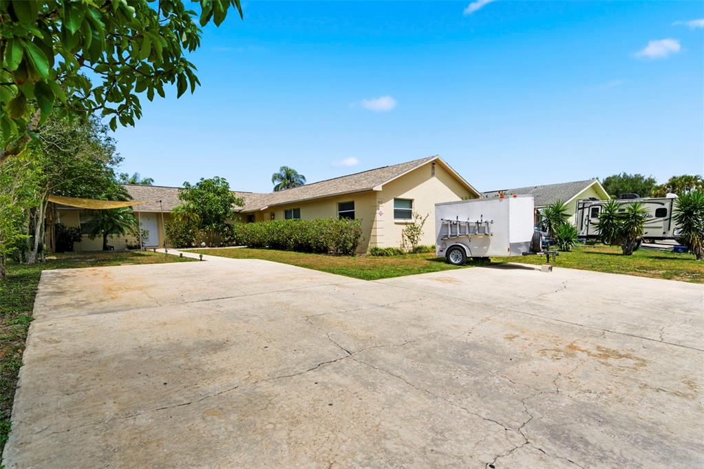 A single-story house with a large concrete driveway, a utility trailer, and an RV parked — 3052 PARK LANE UNIT B, DUNEDIN, FL