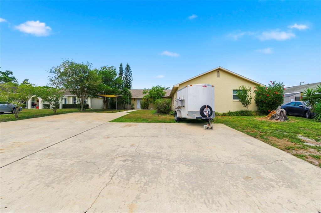 A single-story house with a large concrete driveway and a utility trailer parked outside — 3052 PARK LANE UNIT B, DUNEDIN, FL