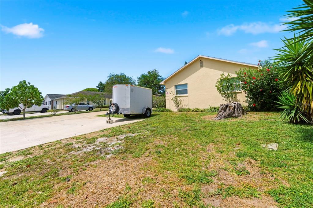 A light-colored house with a concrete driveway, a parked trailer, and a grassy front yard — 3052 PARK LANE UNIT B, DUNEDIN, FL