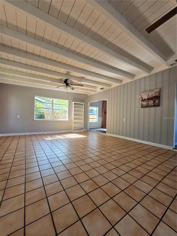A spacious living room features light-colored tile flooring, a beamed ceiling, and vertical wall paneling — 209 W KIRBY STREET, TAMPA, FL